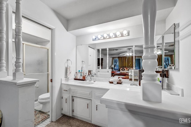 bathroom featuring ceiling fan, vanity, a shower with shower door, and toilet