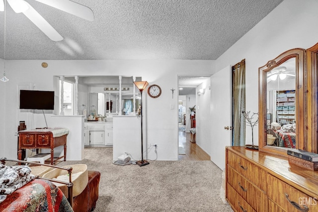 carpeted bedroom featuring ceiling fan, a textured ceiling, and ensuite bath