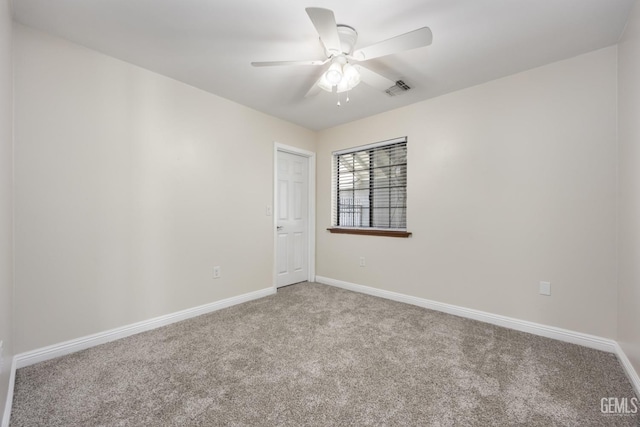 carpeted spare room with baseboards, visible vents, and a ceiling fan