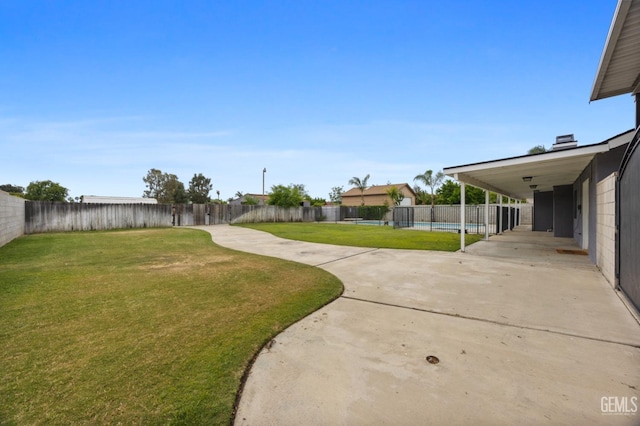 view of yard with concrete driveway, a fenced backyard, a fenced in pool, and a patio area