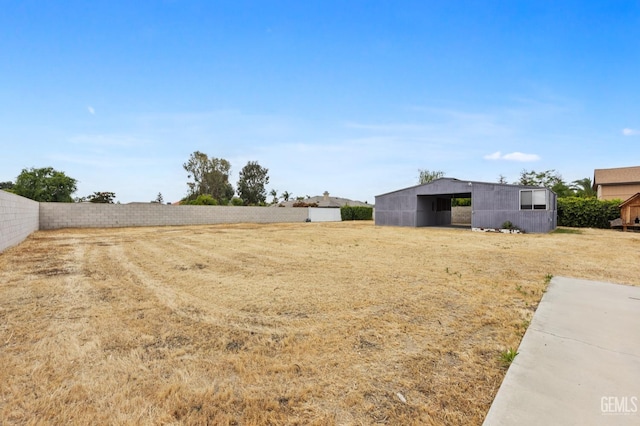 view of yard with an outdoor structure, a pole building, and fence