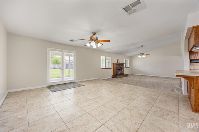 unfurnished living room with light tile patterned floors, a fireplace, visible vents, a ceiling fan, and lofted ceiling