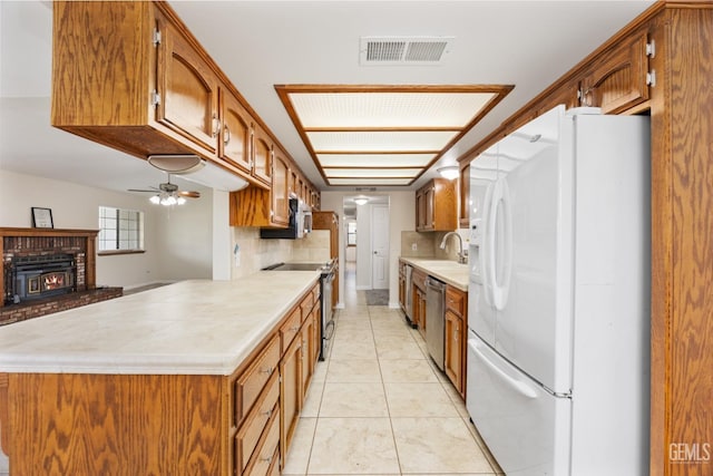 kitchen featuring brown cabinets, decorative backsplash, stainless steel appliances, visible vents, and light countertops