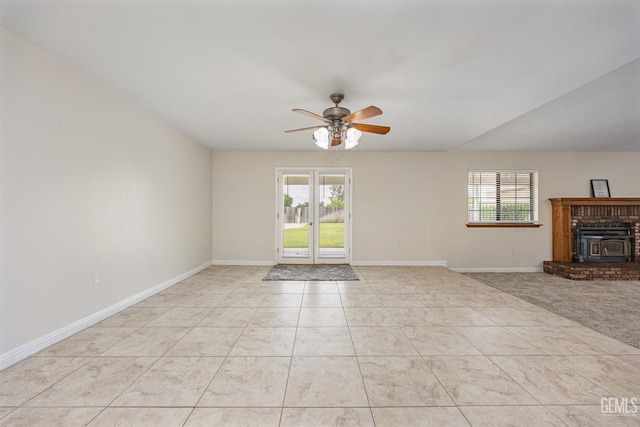 unfurnished living room featuring ceiling fan, a healthy amount of sunlight, a wood stove, and baseboards