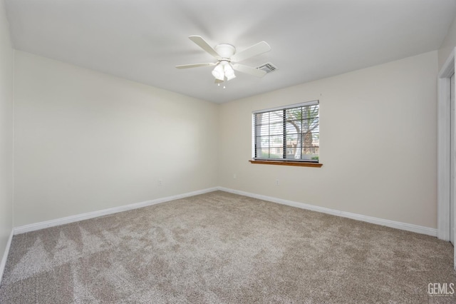 spare room with carpet, visible vents, a ceiling fan, and baseboards