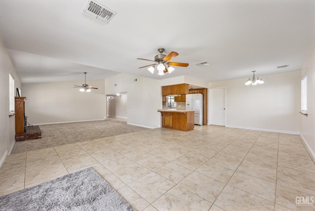 unfurnished living room with baseboards, visible vents, and ceiling fan with notable chandelier