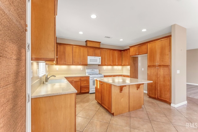 kitchen featuring light tile patterned flooring, sink, a kitchen breakfast bar, a kitchen island, and white appliances