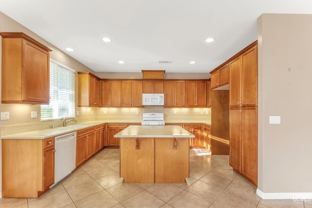 kitchen with sink, a center island, light tile patterned floors, a kitchen breakfast bar, and white appliances