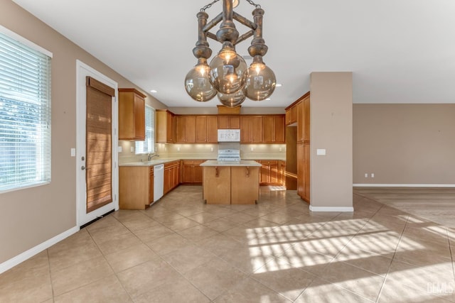 kitchen with pendant lighting, sink, a center island, light tile patterned floors, and white appliances