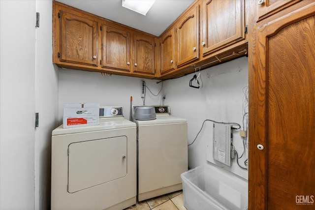 washroom featuring washing machine and dryer, light tile patterned floors, and cabinets