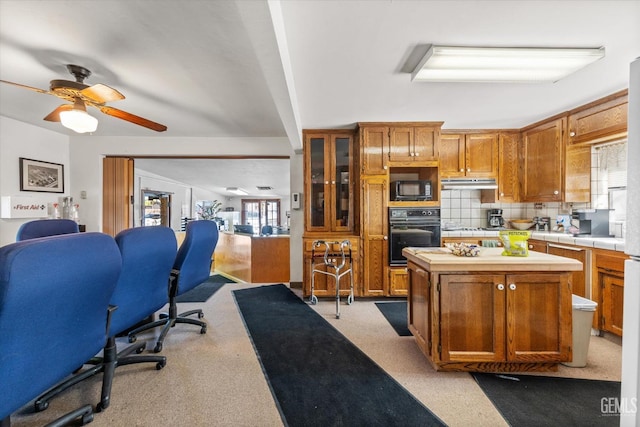 kitchen featuring black appliances, ceiling fan, a center island, and tasteful backsplash