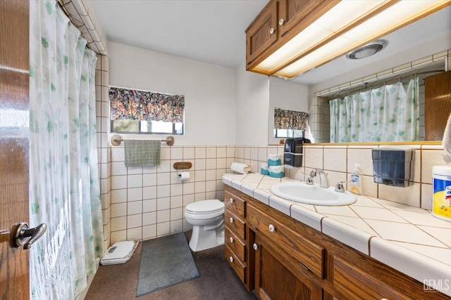 bathroom with a shower with shower curtain, vanity, toilet, and tile walls