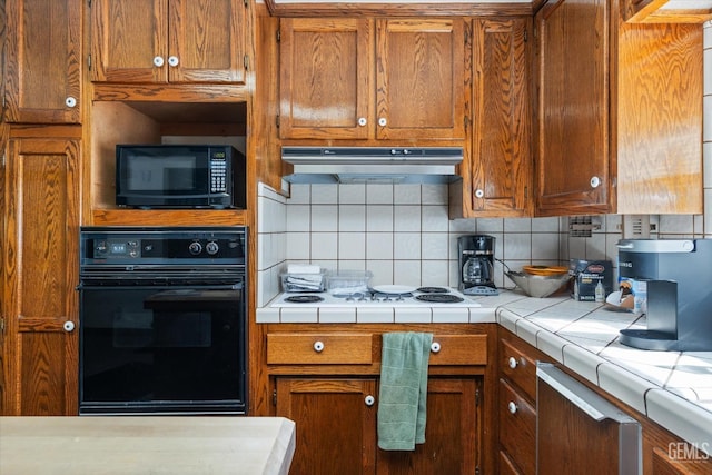 kitchen featuring backsplash, tile counters, and black appliances