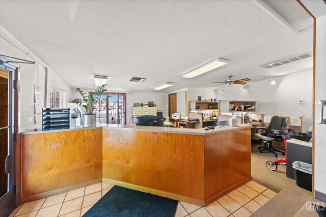 kitchen featuring ceiling fan, kitchen peninsula, a textured ceiling, and light tile patterned floors