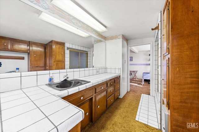 kitchen featuring kitchen peninsula, light carpet, tile counters, and sink