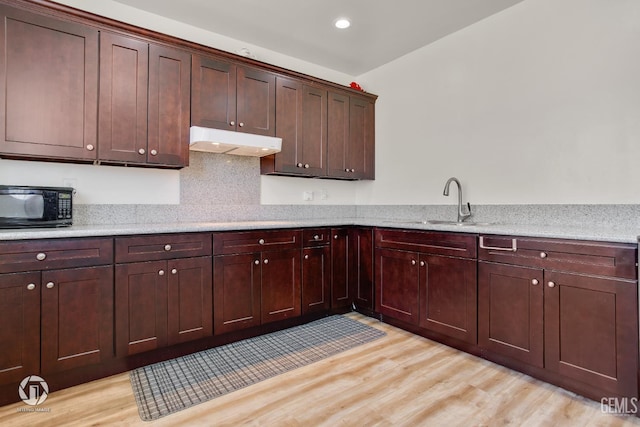 7327 Glitter Way, Bakersfield, CA 93313 - kitchen with black microwave, under cabinet range hood, light wood-style flooring, recessed lighting, and backsplash