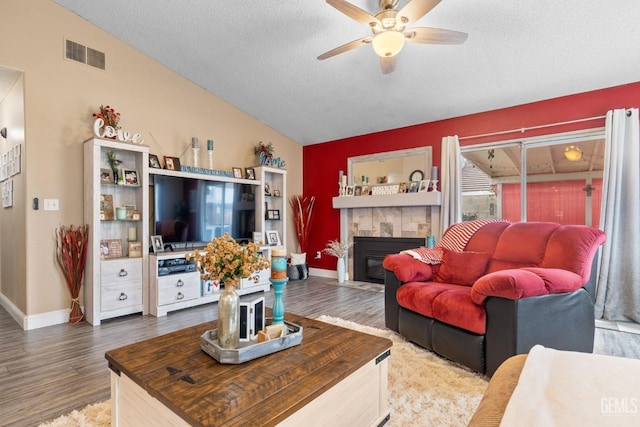 living room featuring ceiling fan, vaulted ceiling, wood finished floors, and visible vents