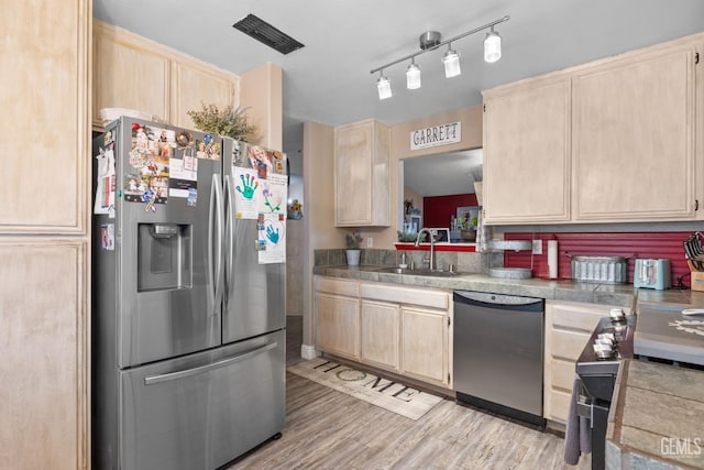 kitchen featuring stainless steel appliances, visible vents, a sink, and light brown cabinets