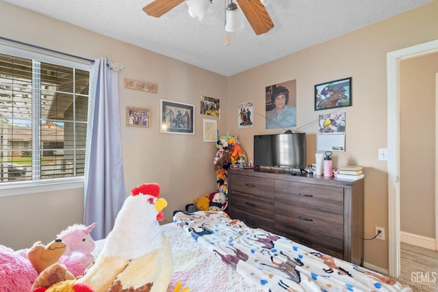 bedroom with a textured ceiling, baseboards, multiple windows, and ceiling fan