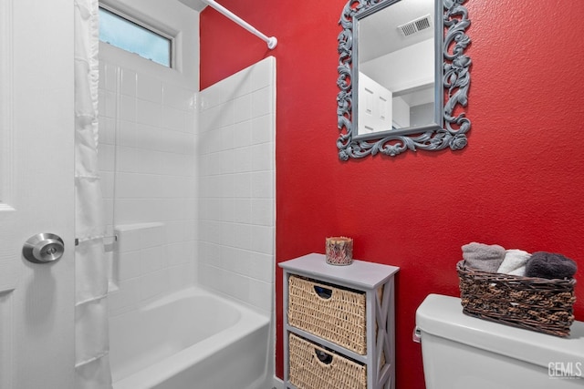 bathroom with visible vents, a textured wall, toilet, and shower / tub combo