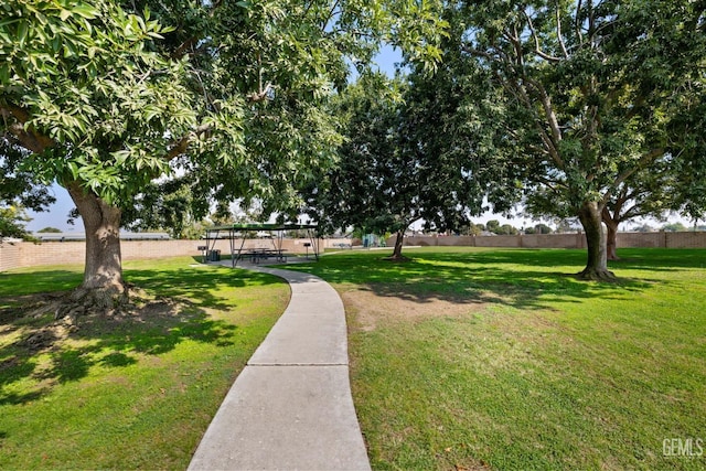 view of property's community with a lawn and fence