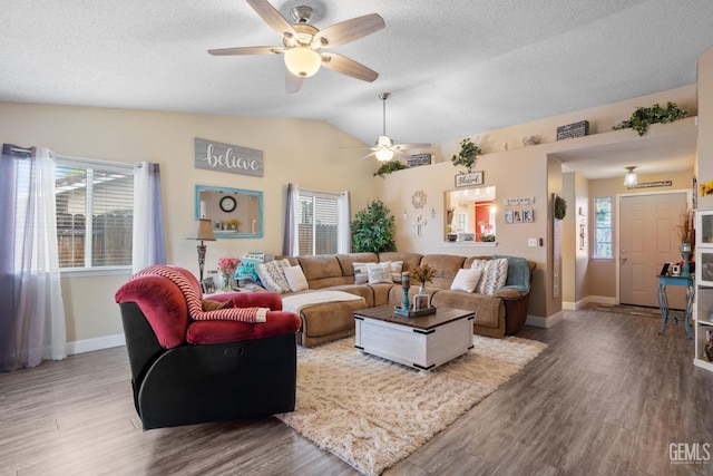 living area featuring ceiling fan, a textured ceiling, baseboards, wood finished floors, and lofted ceiling