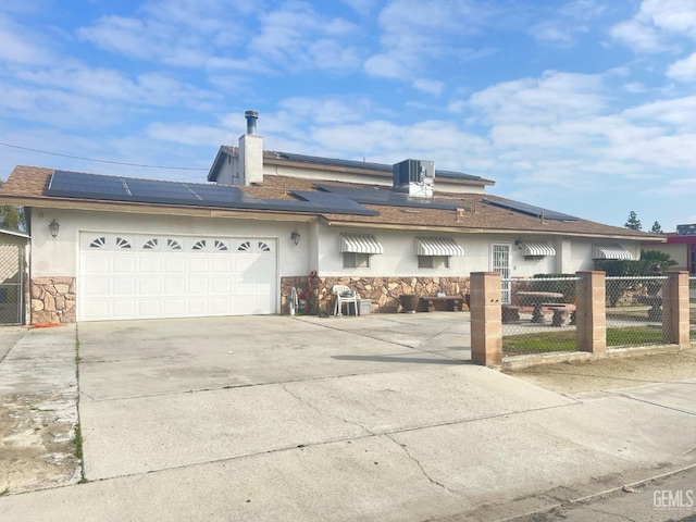 view of front facade featuring cooling unit, a garage, and solar panels