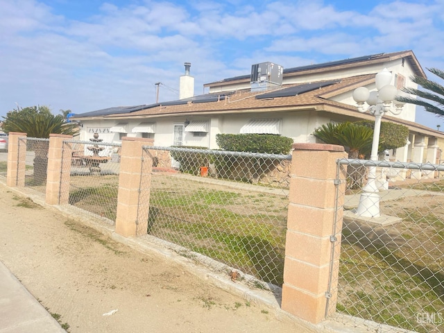 view of gate featuring central AC unit and solar panels