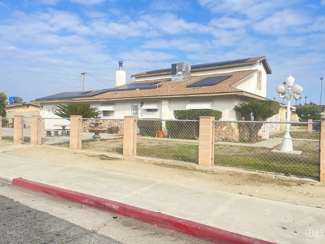 view of front of home with cooling unit and solar panels