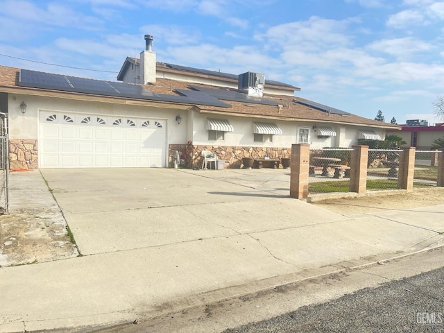 single story home with a garage, cooling unit, and solar panels