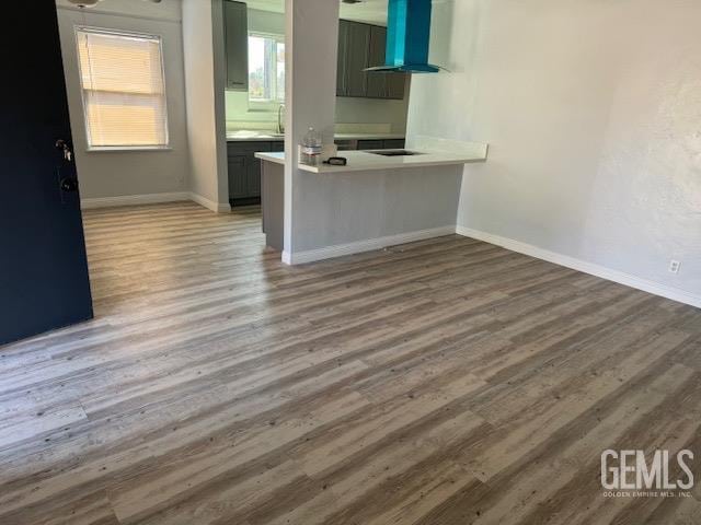 kitchen with kitchen peninsula, hardwood / wood-style floors, and wall chimney exhaust hood