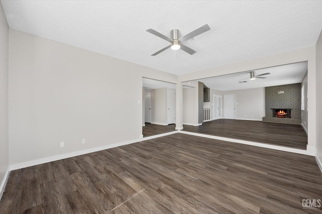 unfurnished living room with ceiling fan, a brick fireplace, and a textured ceiling