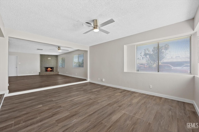 unfurnished living room featuring dark hardwood / wood-style flooring, a textured ceiling, a fireplace, and ceiling fan