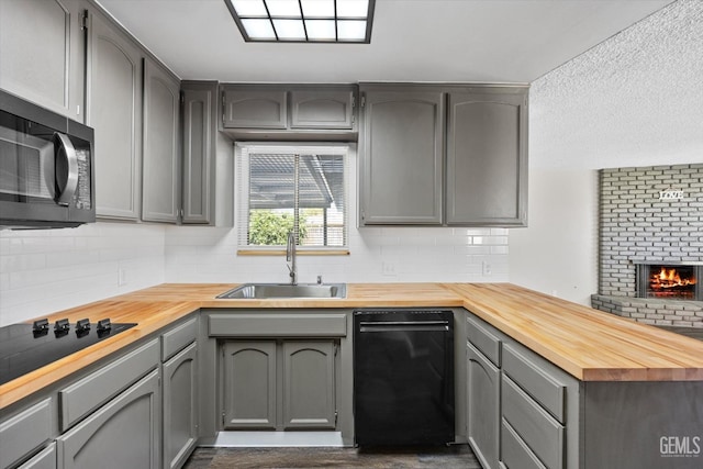 kitchen with wood counters, sink, black appliances, and gray cabinetry