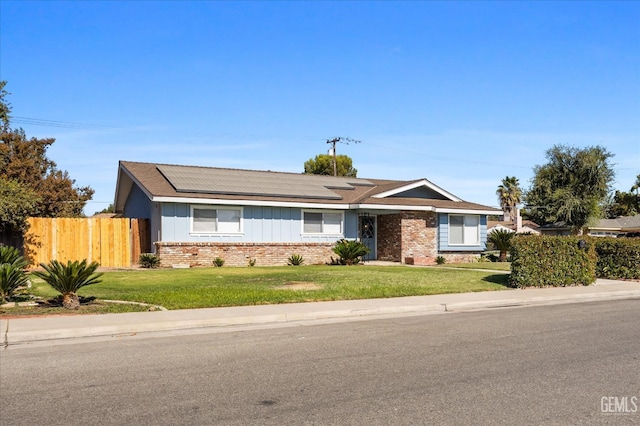 ranch-style home with a front lawn and solar panels