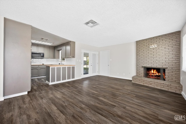 unfurnished living room with dark wood-type flooring, a fireplace, and a textured ceiling