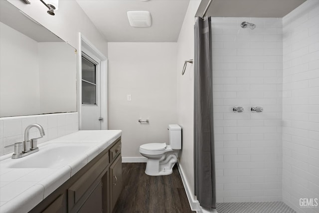 bathroom with tiled shower, vanity, tasteful backsplash, wood-type flooring, and toilet