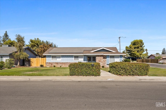 single story home with a front lawn and solar panels