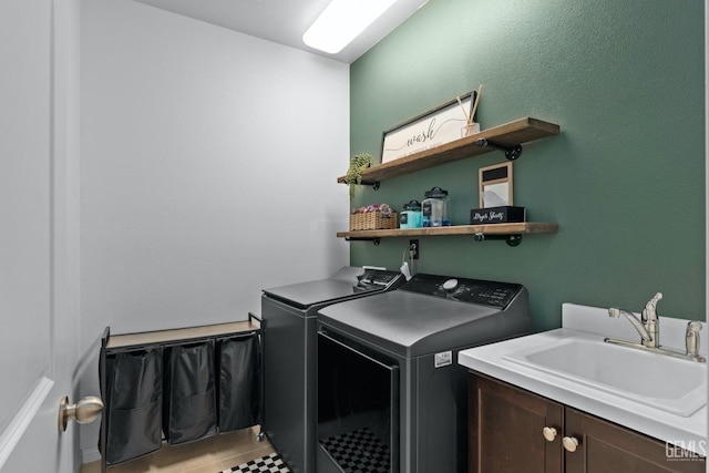 laundry room featuring washing machine and clothes dryer, cabinet space, and a sink