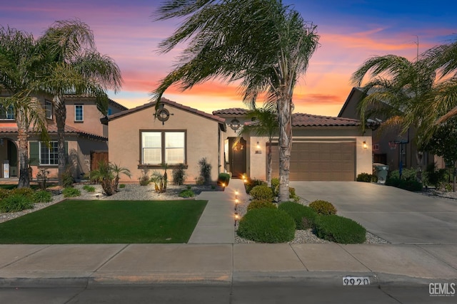 mediterranean / spanish-style house featuring a front lawn, a tiled roof, stucco siding, driveway, and an attached garage