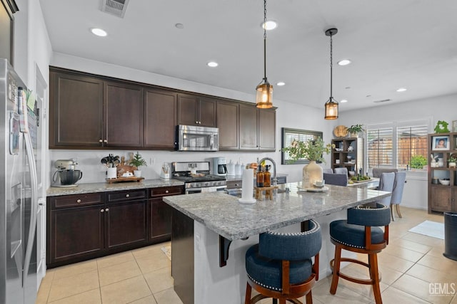 kitchen with light tile patterned floors, visible vents, a kitchen breakfast bar, and stainless steel appliances