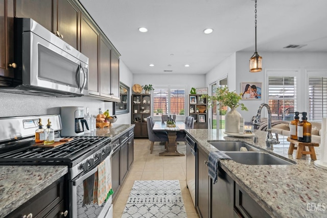 kitchen featuring light stone counters, light tile patterned flooring, recessed lighting, a sink, and stainless steel appliances