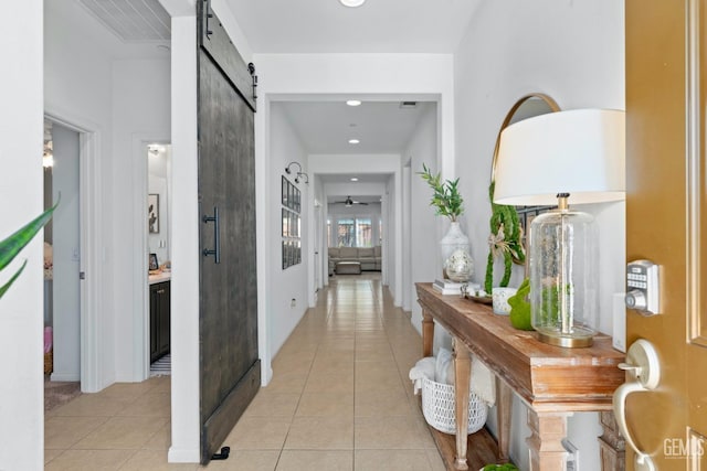 hallway featuring light tile patterned floors, a barn door, and recessed lighting