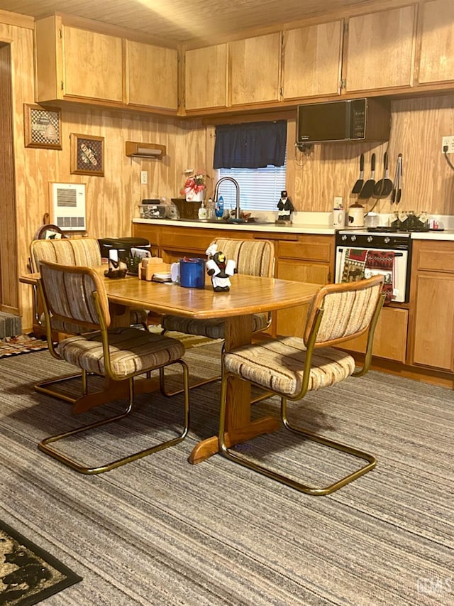 kitchen with extractor fan, oven, wooden walls, and sink