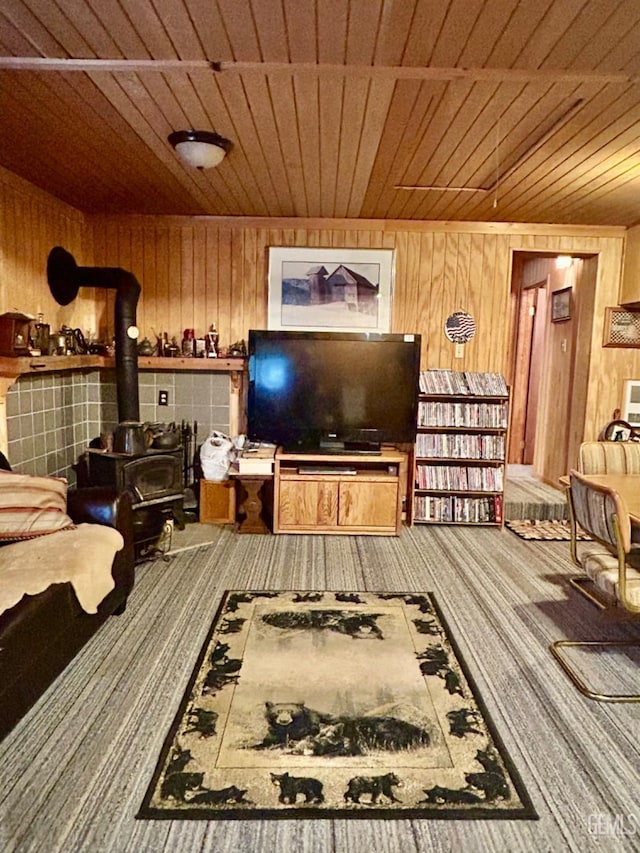 living room with a wood stove, wooden walls, carpet, and wooden ceiling