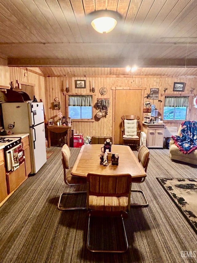 carpeted dining room with beam ceiling, wood walls, and wooden ceiling