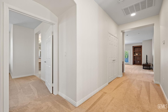 corridor featuring light colored carpet, baseboards, and visible vents