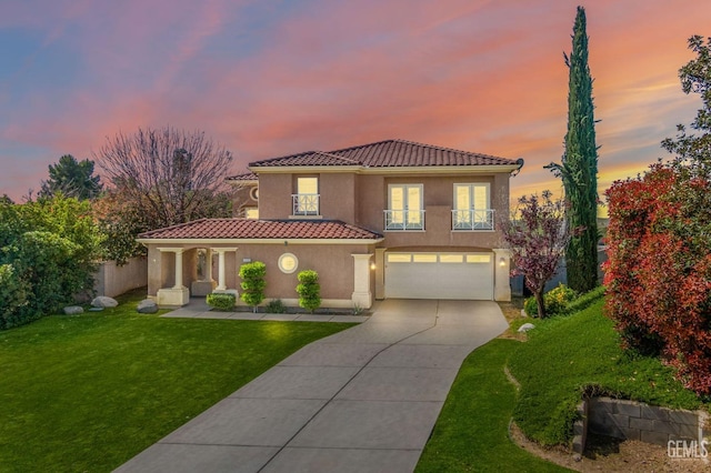 mediterranean / spanish-style house featuring a tile roof, concrete driveway, a garage, a balcony, and a front yard