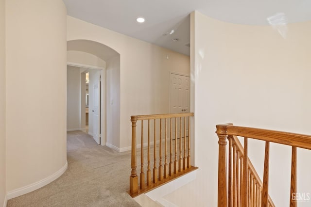 corridor featuring an upstairs landing, arched walkways, carpet, baseboards, and recessed lighting