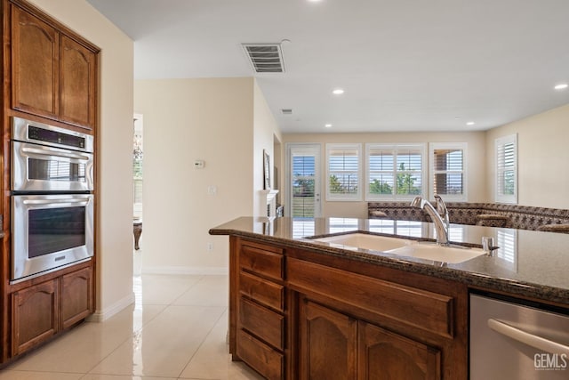 kitchen with a sink, dark stone counters, visible vents, appliances with stainless steel finishes, and light tile patterned floors